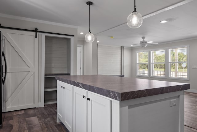 kitchen featuring a barn door, decorative light fixtures, dark hardwood / wood-style floors, a center island, and white cabinetry