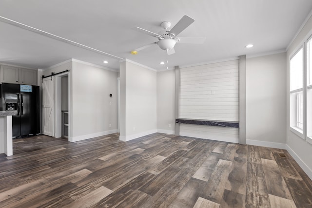 unfurnished living room featuring a wealth of natural light, a barn door, and dark hardwood / wood-style flooring