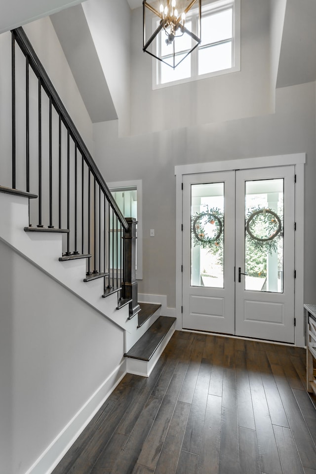 foyer with a towering ceiling, dark hardwood / wood-style flooring, a notable chandelier, and french doors