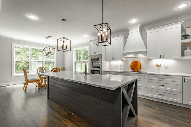 kitchen with decorative light fixtures, dark hardwood / wood-style floors, an island with sink, and custom range hood