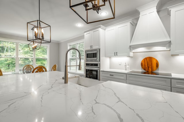 kitchen featuring an inviting chandelier, light stone countertops, stainless steel appliances, and custom exhaust hood