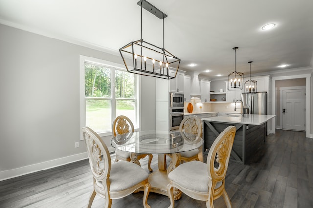 dining room featuring dark wood-type flooring, ornamental molding, and sink