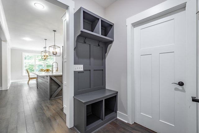 mudroom featuring dark wood-type flooring and a chandelier