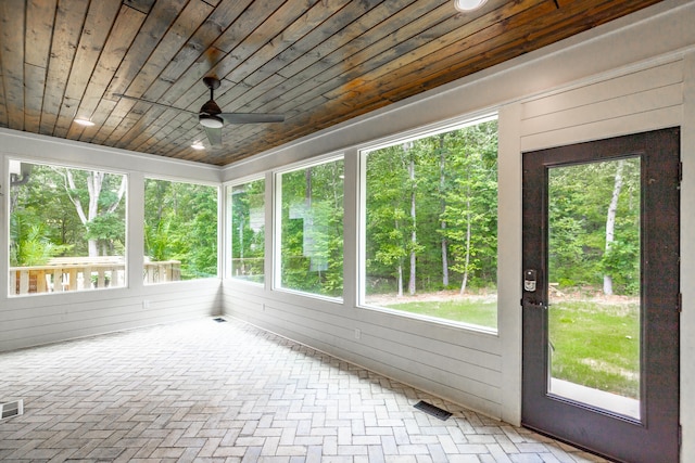 unfurnished sunroom featuring ceiling fan, wooden ceiling, and a healthy amount of sunlight