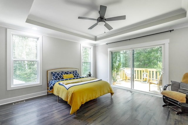 bedroom with dark hardwood / wood-style flooring, a tray ceiling, ceiling fan, and multiple windows