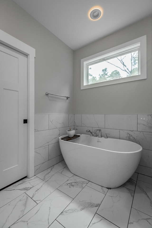 bathroom featuring a bath and tile walls