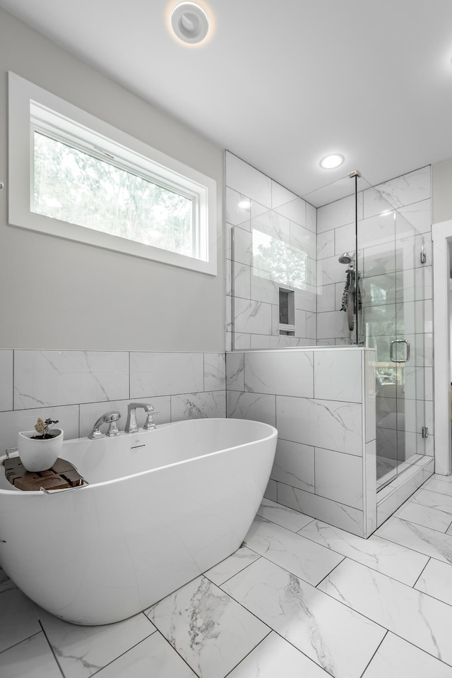 bathroom featuring tile walls and independent shower and bath