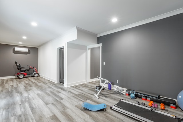 exercise room with ornamental molding, a wall mounted air conditioner, and light hardwood / wood-style flooring