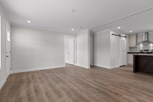 unfurnished living room with light hardwood / wood-style floors, crown molding, and a barn door