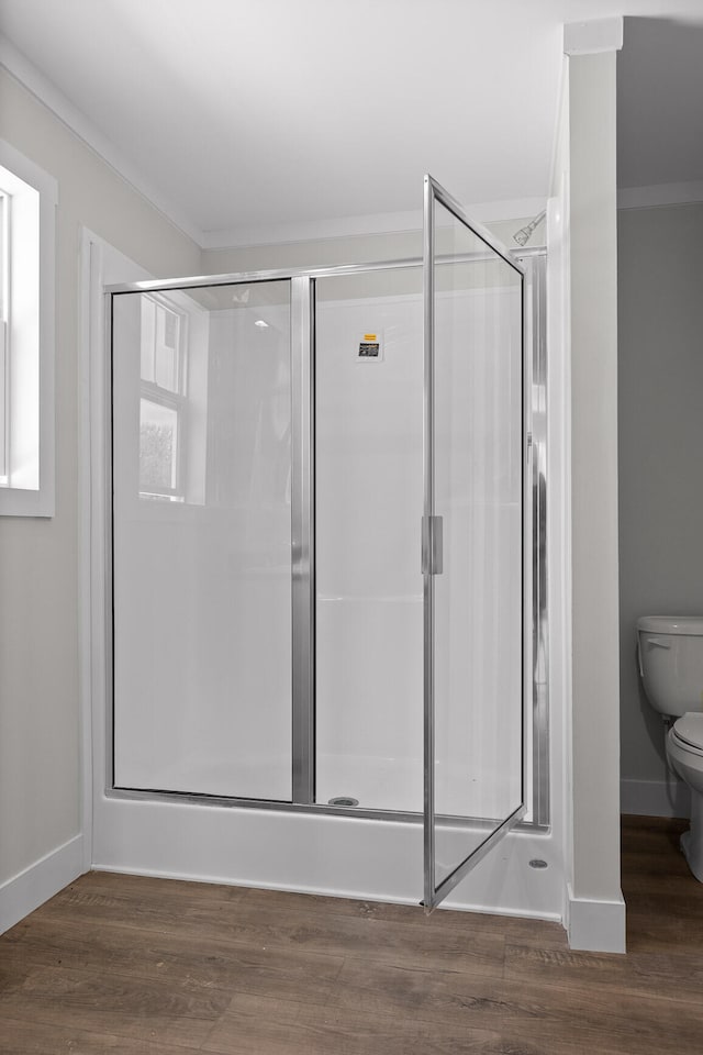 bathroom featuring hardwood / wood-style flooring, an enclosed shower, crown molding, and toilet