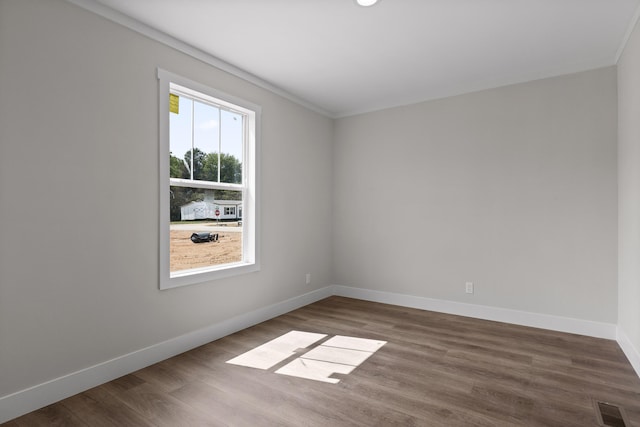 spare room featuring crown molding, hardwood / wood-style floors, and a wealth of natural light