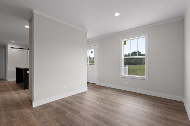 unfurnished room featuring dark hardwood / wood-style floors, ornamental molding, and a healthy amount of sunlight