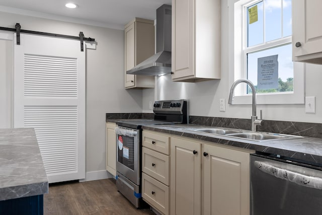 kitchen with sink, wall chimney exhaust hood, stainless steel appliances, a barn door, and dark hardwood / wood-style flooring