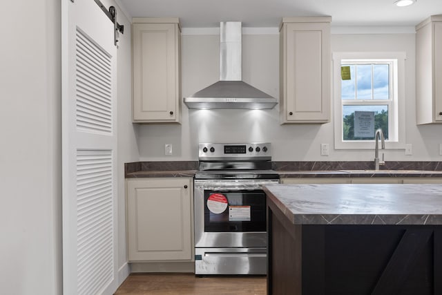 kitchen featuring sink, wall chimney exhaust hood, white cabinetry, stainless steel range with electric cooktop, and a barn door