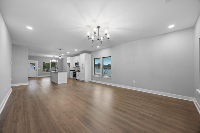 unfurnished living room featuring dark wood-type flooring, a wealth of natural light, and an inviting chandelier