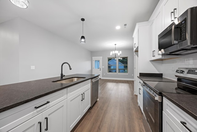 kitchen with white cabinetry, stainless steel appliances, sink, and decorative light fixtures