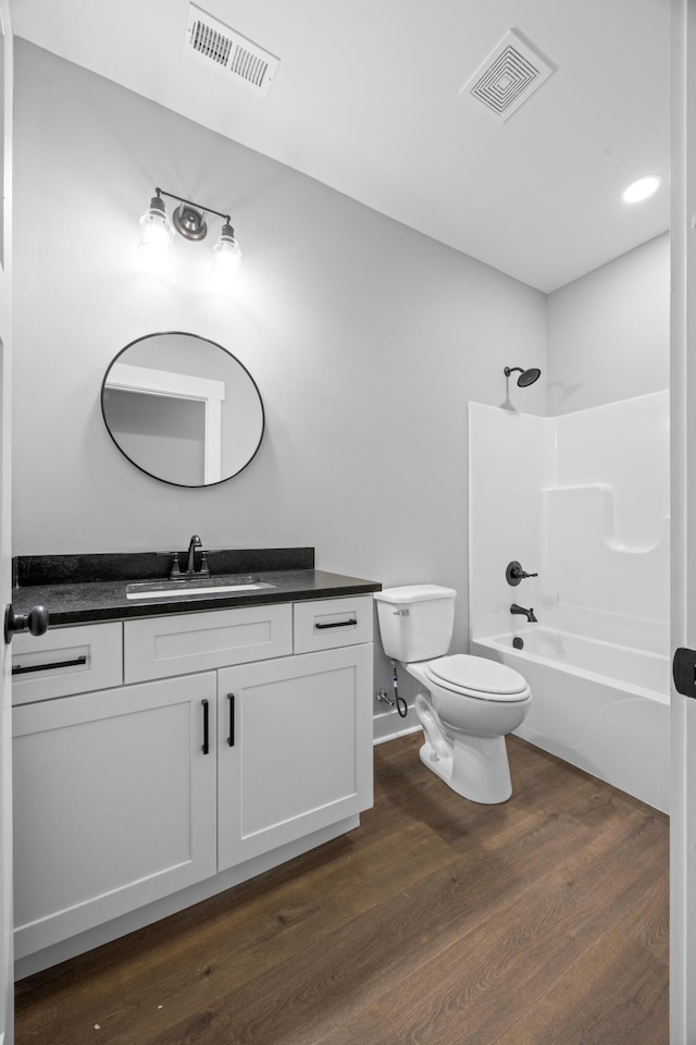 full bathroom featuring hardwood / wood-style floors, shower / washtub combination, toilet, and vanity