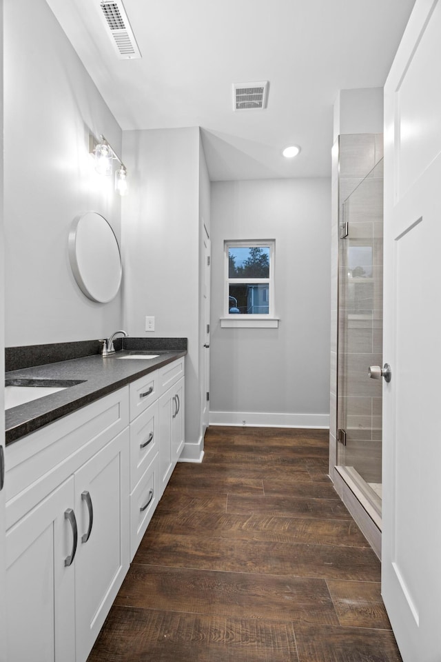 bathroom with wood-type flooring, vanity, and a shower with shower door