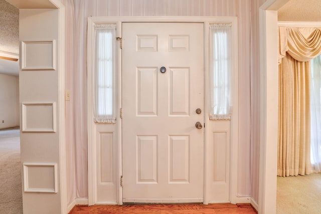 foyer with a textured ceiling and light colored carpet