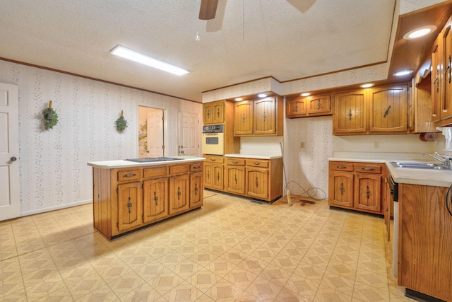 kitchen featuring oven, crown molding, sink, ceiling fan, and a textured ceiling