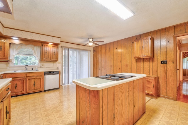 kitchen featuring dishwasher, wooden walls, a center island, ceiling fan, and a textured ceiling