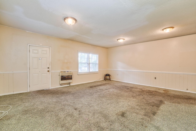 carpeted empty room with heating unit and a textured ceiling