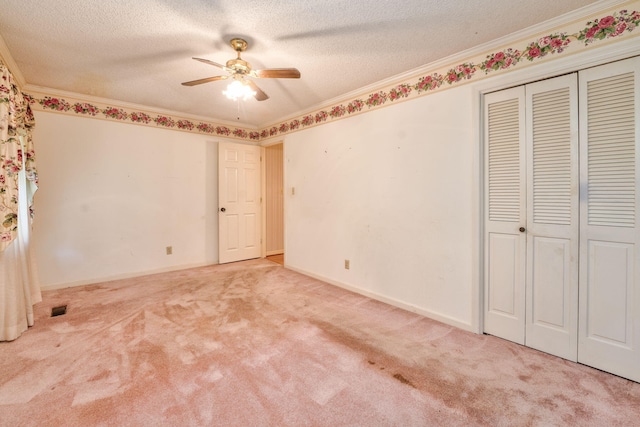 unfurnished bedroom with crown molding, a textured ceiling, ceiling fan, a closet, and carpet floors