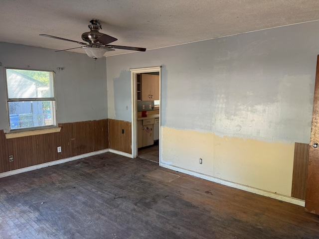 unfurnished room featuring a textured ceiling, ceiling fan, and wood walls