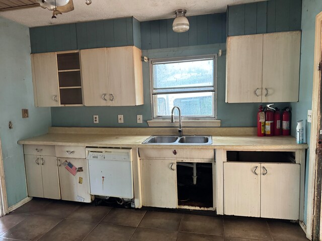 kitchen with white dishwasher, dark tile patterned floors, and sink