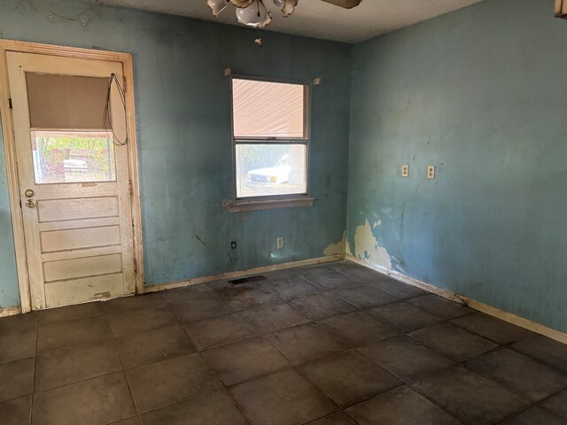 empty room with dark tile patterned floors and ceiling fan