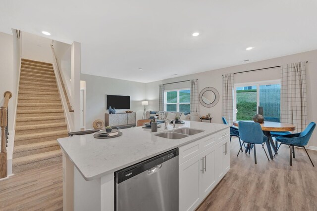 kitchen featuring light wood-type flooring, dishwasher, an island with sink, sink, and white cabinets