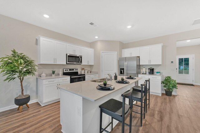 kitchen featuring light hardwood / wood-style flooring, stainless steel appliances, white cabinetry, sink, and an island with sink