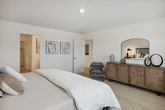 bedroom with connected bathroom, light carpet, and a textured ceiling