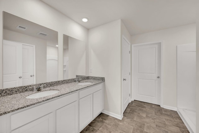 bathroom featuring double vanity, baseboards, visible vents, and a sink