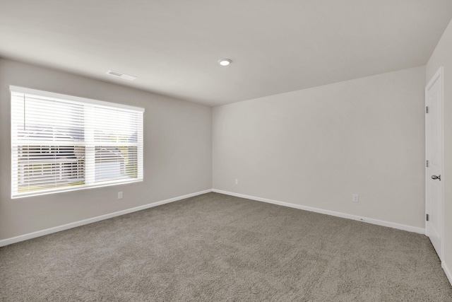 spare room featuring visible vents, carpet, and baseboards