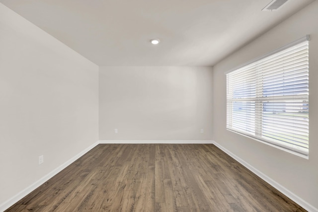empty room featuring visible vents, baseboards, and dark wood finished floors