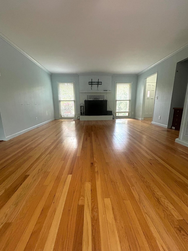 unfurnished living room featuring light hardwood / wood-style floors, a wealth of natural light, and ornamental molding