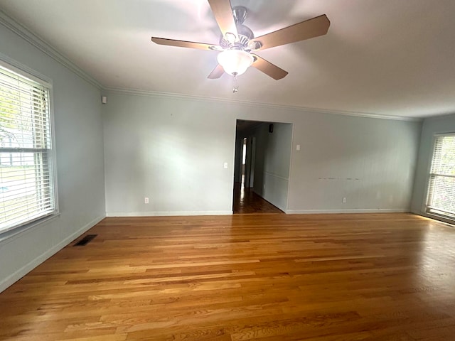 spare room featuring plenty of natural light, ornamental molding, and light wood-type flooring