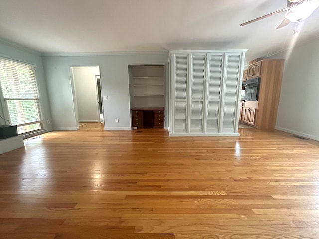 unfurnished living room with ceiling fan, built in features, crown molding, and light hardwood / wood-style flooring