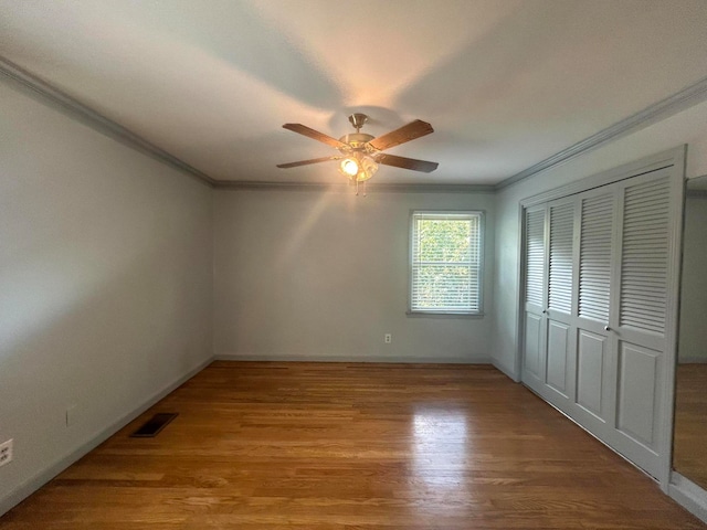 empty room with light wood-type flooring, ceiling fan, and ornamental molding