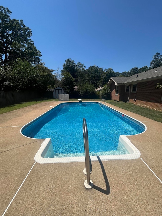 view of pool with a storage shed, a diving board, and a patio