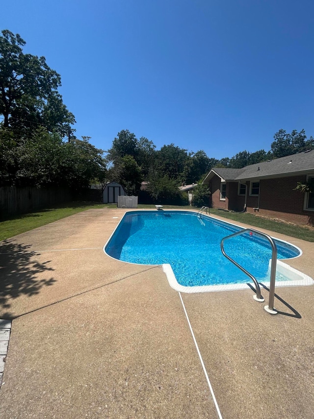 view of pool featuring a patio area, a diving board, and a storage unit