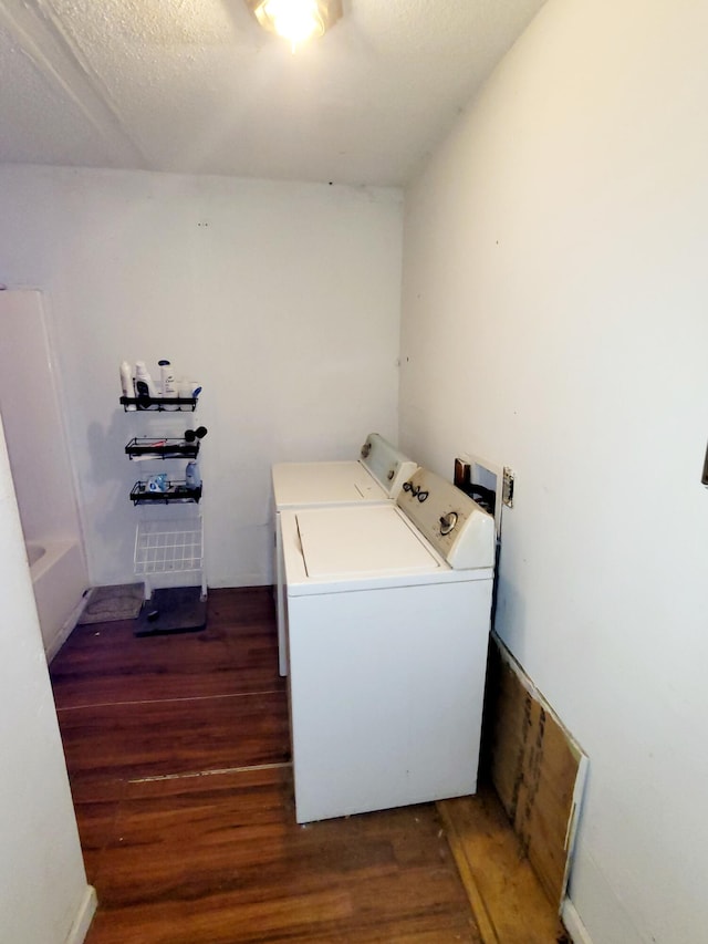 clothes washing area featuring a textured ceiling, dark hardwood / wood-style floors, and washing machine and clothes dryer