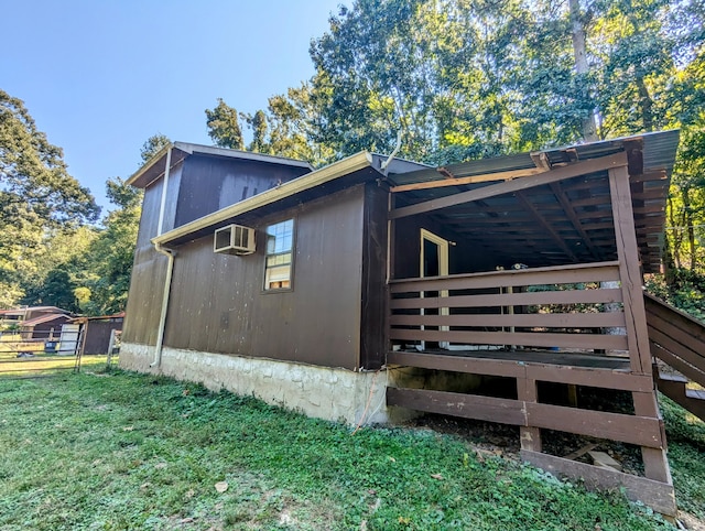 view of side of home featuring a deck, a yard, and a wall unit AC