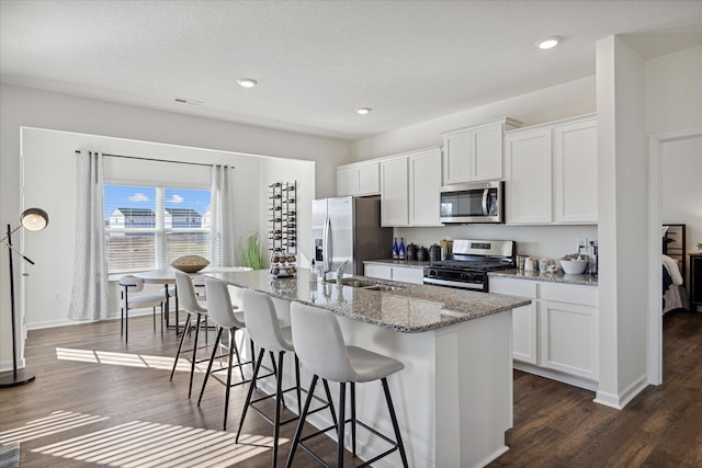 kitchen featuring white cabinets, dark hardwood / wood-style flooring, stainless steel appliances, and a center island with sink