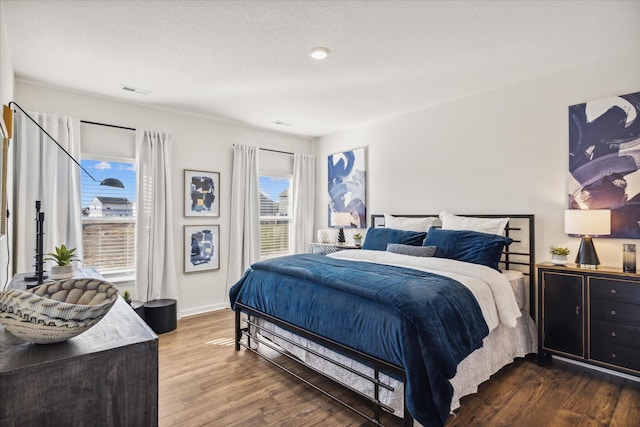 bedroom featuring multiple windows, a textured ceiling, and hardwood / wood-style flooring