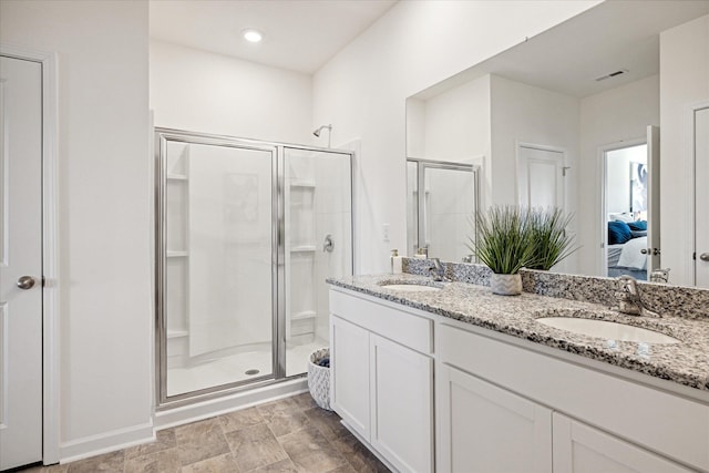 bathroom featuring a shower with door and vanity