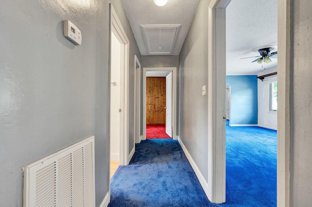 hall with carpet flooring, baseboards, visible vents, and attic access