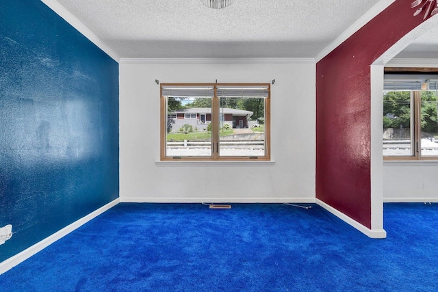 carpeted spare room featuring crown molding, arched walkways, a textured ceiling, and baseboards