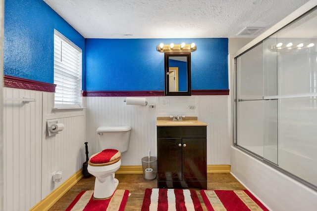 full bathroom with a textured ceiling, wainscoting, wood finished floors, vanity, and toilet